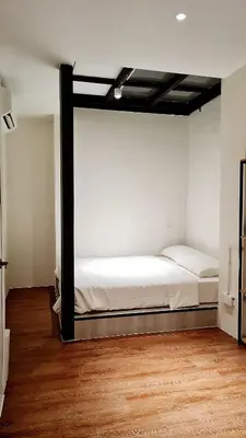 a bed in a room with white walls and wood floors at Stewart Hotel at 67 By EVR - Newly Renovated 2024 in George Town