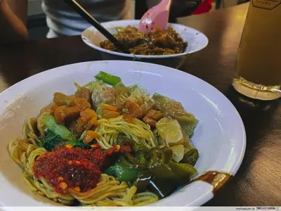 a plate of pasta with meat and vegetables on a table at Stewart Hotel at 67 By EVR - Newly Renovated 2024 in George Town