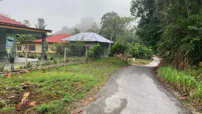 a dirt road next to a house and a yard at Homestay Fida in Gerik