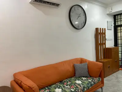a living room with a couch and a clock on the wall at Jessie Home in Bukit Mertajam