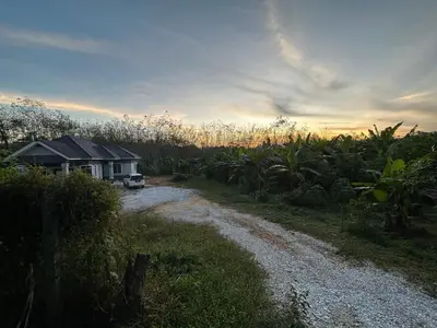 a house and a dirt road next to a field at D’Asam Homestay Baling in Baling