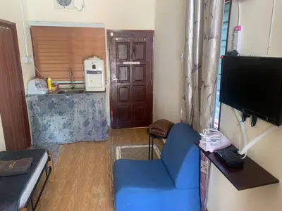a living room with a blue chair and a television at Chalet Naqib in Gerik