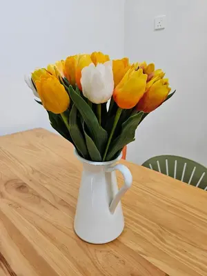 a white vase filled with yellow and white flowers on a table at Air-home No 28 Simpang near Aulong Econsave, 3BR, 7pax, Netflix in Simpang