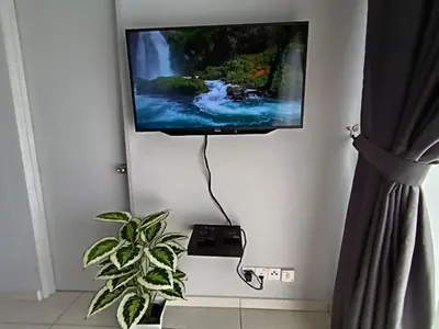 a flat screen tv hanging on a wall with a plant at The Horizon Ipoh Dual L12 by Grab A Stay in Ipoh