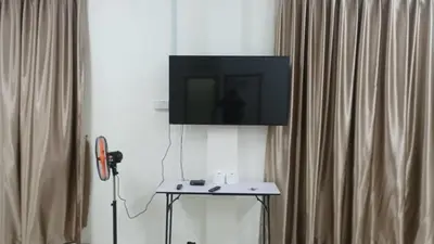 a television on a wall next to a table with a tv at Happy homestay in Teluk Intan
