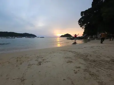 a person standing on a beach with their arms in the air at ShopLot Hostel Pangkor in Pasir Bogak