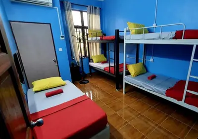 a room with three bunk beds and a red bench at ShopLot Hostel Pangkor in Pasir Bogak