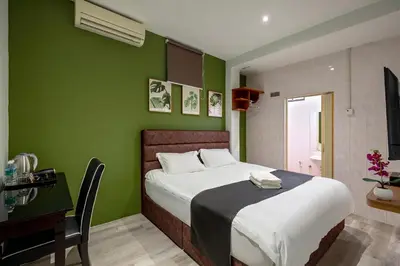 a bedroom with green walls and a bed and a desk at GAIA Hotel in Tanjung Bungah
