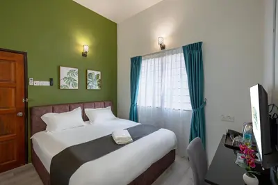 a bedroom with a bed with green walls and a window at GAIA Hotel in Tanjung Bungah