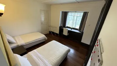 a small room with two beds and a window at Bukit Ruil Bungalow - Clementine Suite in Tanah Rata