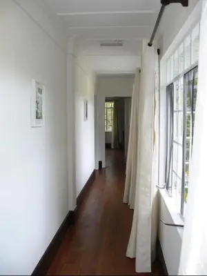 a hallway with white walls and wooden floors and windows at Bukit Ruil Bungalow - Clementine Suite in Tanah Rata