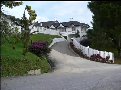 a house with a white fence and a driveway at Bukit Ruil Bungalow - Clementine Suite in Tanah Rata