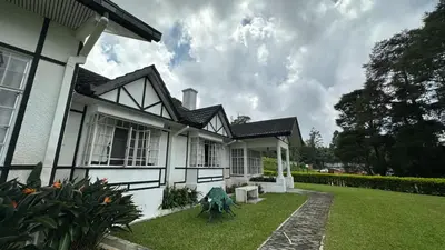 a white house with a grass yard in front of it at Bukit Ruil Bungalow - Clementine Suite in Tanah Rata