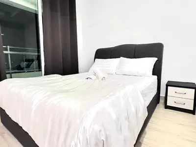 a large bed with white sheets and a black headboard at Leisure 1Bedroom Balcony Suites Gurney in George Town