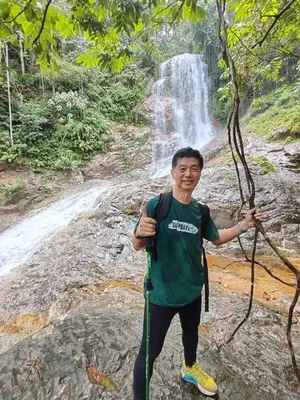 a man standing in front of a waterfall at Sunny Lake House - Entire bungalow, 5 rooms, 16 persons in Behrang Hulu