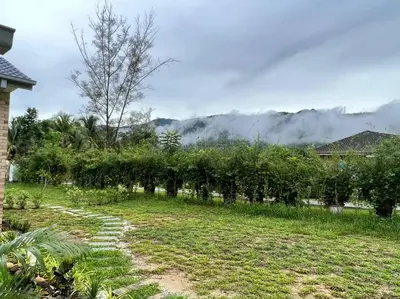a path in a garden with trees and clouds in the background at Sunny Lake House - Entire bungalow, 5 rooms, 16 persons in Behrang Hulu