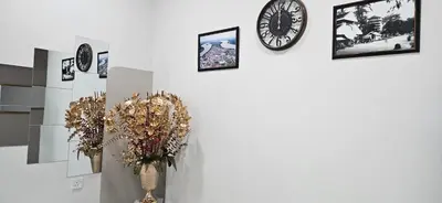 a wall with clocks and a vase with flowers on it at Teluk Intan Homestay Landed 3BR2B in Teluk Intan