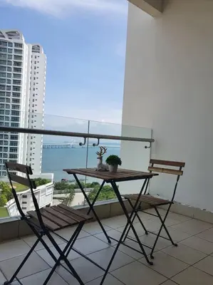 a table and chairs on a balcony with a view of the ocean at Southbay Seaview Condo A16 #10minQueensbay #15minSPICE in Bayan Lepas