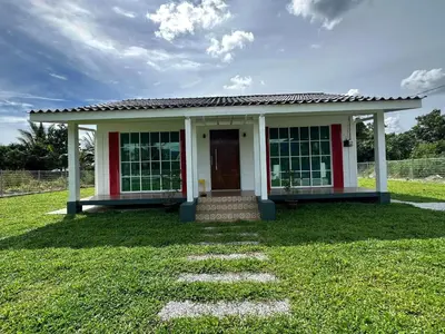 a small white house with a grass yard at Tiny House PT82 Kg Gumut Tambahan in Kalumpang