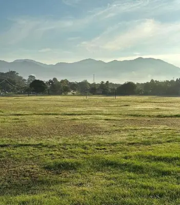 a field of grass with mountains in the distance at Tiny House PT82 Kg Gumut Tambahan in Kalumpang
