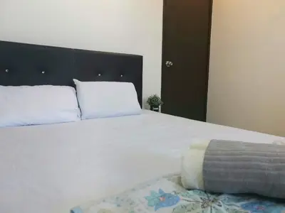a bedroom with a large white bed with a black headboard at White House 19 Room B in Bukit Mertajam