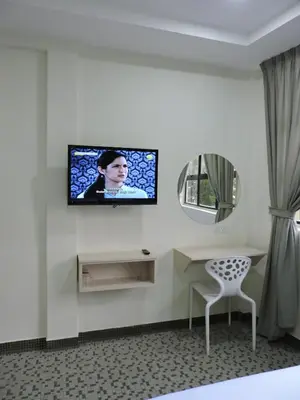 a room with a television on a wall with a chair at Merlin Hotel George Town Penang in George Town