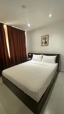 a bedroom with a large bed with white sheets at Hotel Vistana Micassa in Taiping