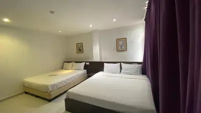two beds in a hotel room with purple curtains at Hotel Vistana Micassa in Taiping
