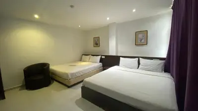 a hotel room with two beds and a chair at Hotel Vistana Micassa in Taiping