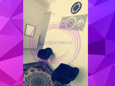 a room with two chairs and a clock on the wall at The Clemira Homestay @ Sungai Karangan, Kulim, Kedah in Padang Serai
