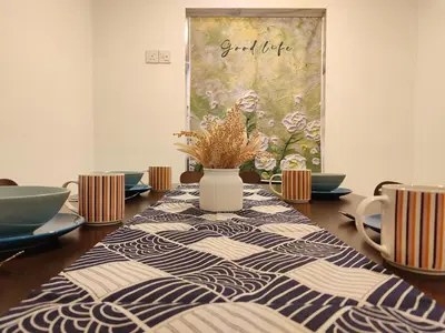 a dining room table with a vase with flowers in it at Golden 78 Ipoh Homestay in Ipoh