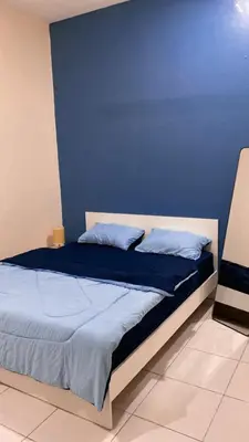 a bedroom with a bed with a blue wall at Rumah Aidin Homestay in Sitiawan