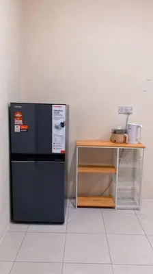 a black refrigerator sitting next to a table at Rumah Aidin Homestay in Sitiawan