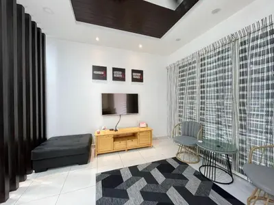 a living room with a television and a table at Thetamu Homestay مسلم Kepala Batas in Kepala Batas