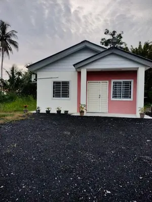 a white and red house with a gravel driveway at AZK HOMESTAY in Sungai Besar