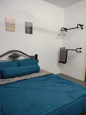 a bedroom with a bed with blue sheets and a lamp at AZK HOMESTAY in Sungai Besar