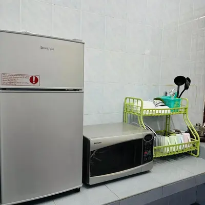 a microwave sitting next to two refrigerators on a counter at CYC homestay 18 pax in Kampong Batu Lapan