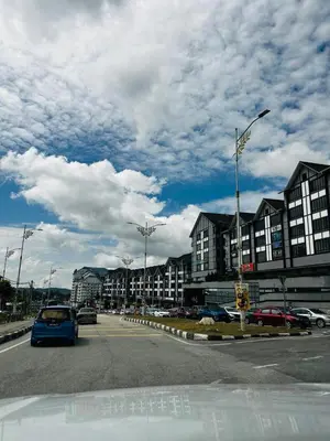 a blue car driving down a street with buildings at Adamhawa Homestay Emerald Avenue Brinchang in Brinchang