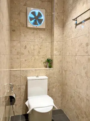 a bathroom with a toilet with a blue wheel on the wall at Asimmy Hotel in Kampong Gurun
