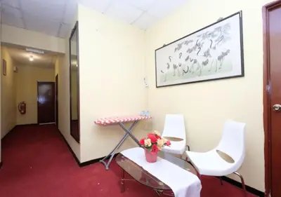 a room with two chairs and a table with a vase of flowers at Hotel Tudor Home Inn Cameron Highlands in Brinchang