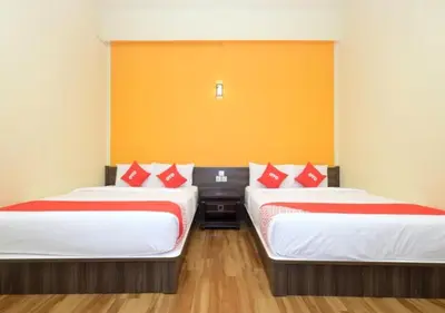 two beds in a room with red and white pillows at Hotel Tudor Home Inn Cameron Highlands in Brinchang