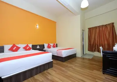 a hotel room with two beds with red pillows at Hotel Tudor Home Inn Cameron Highlands in Brinchang