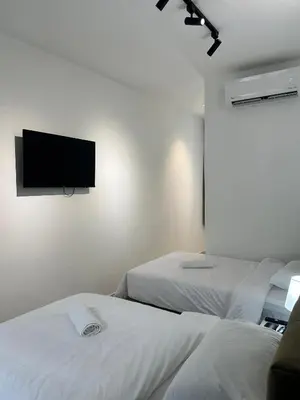 a room with two beds and a flat screen tv on the wall at Lodge 43 House in George Town