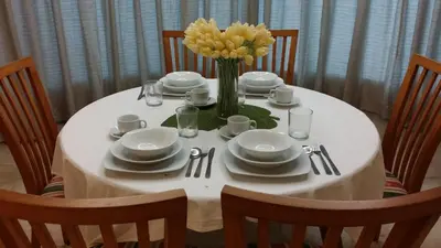 a white table with a vase of yellow flowers on it at Tropical Sea View & Sunshine in Batu Ferringhi