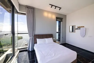 a bedroom with a white bed and a large window at Urban Suites with Spectacular High Floor View #3BR #03 in Jelutong