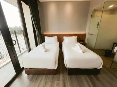 two beds in a hotel room with windows at Crosview in Kampung Sepetang