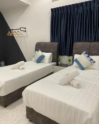 two beds in a room with blue curtains at IPOH LYL EVERGREEN HOMESTAY 12pax in Ipoh
