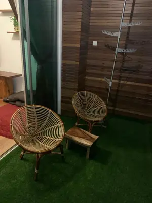 two rattan chairs sitting next to a room with green carpet at HappyHomestay in Brinchang