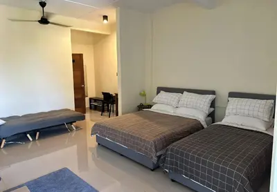 a bedroom with two beds and a table at Nibong Tebal Studio Home Stay in Nibung Tebal