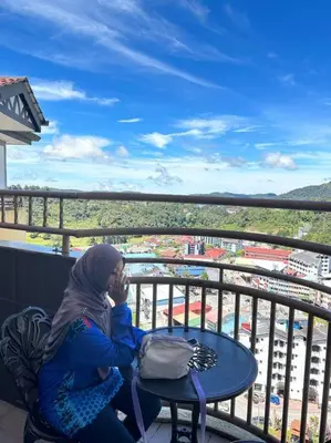 a man sitting at a table on a balcony at Zurie Muslim Homestay in Brinchang